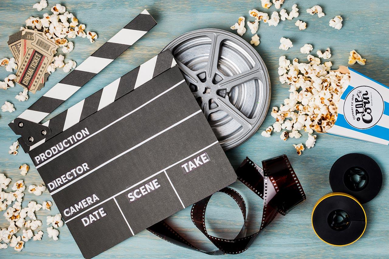 movie slate, spilt popcorn, movie tickets, and movie reels