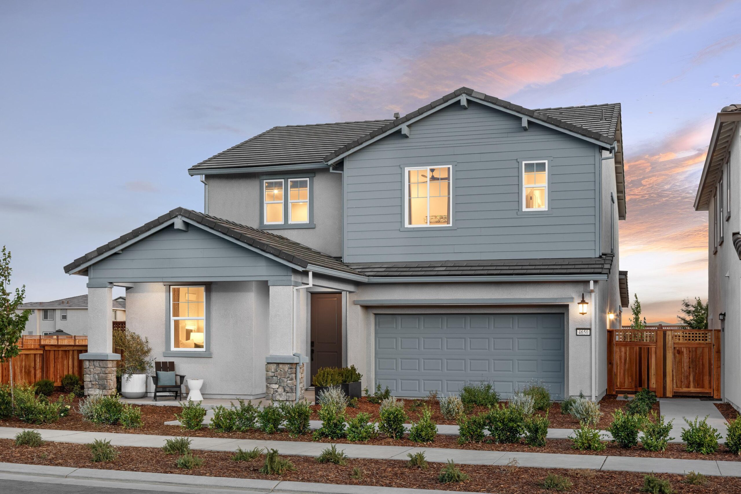 Two-story exterior of Bridgeway Plan 3503 by New Home Company at River Islands with blue siding accents, two-car garage, and landscaped front yard.